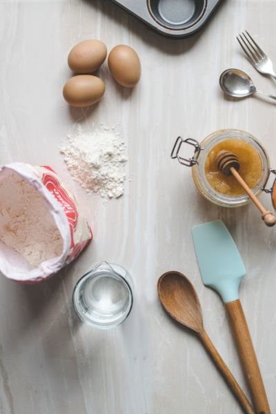 baking supplies, mixing spoons, 3 eggs, fork and spoon set up on a counter