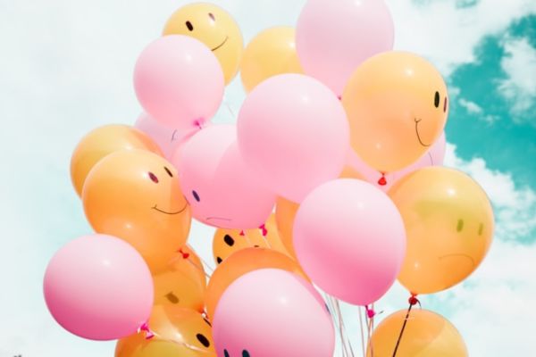 pink and orange balloons with happy faces on them