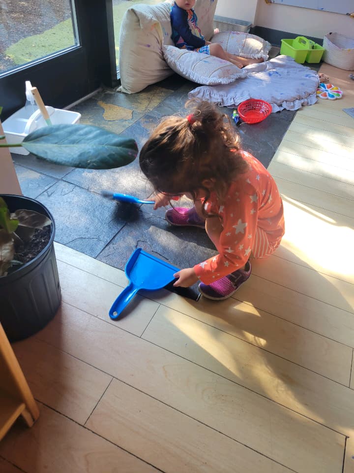 my toddler cleaning up the ground with a dustpan