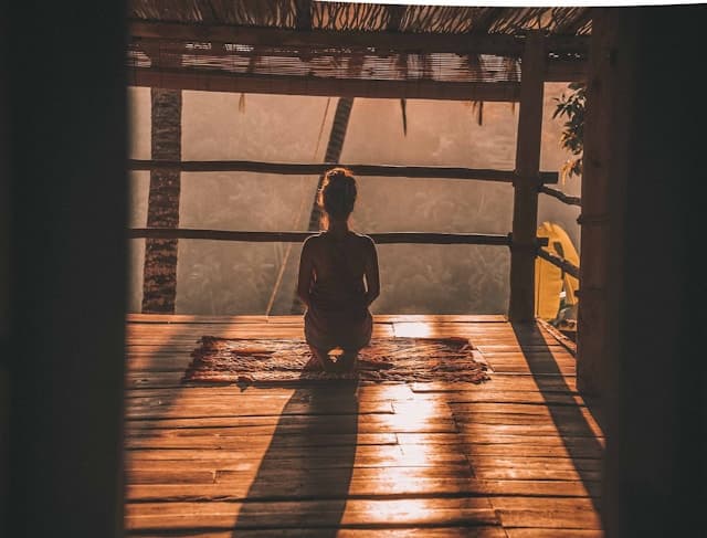 person facing nature and doing meditation on a rug