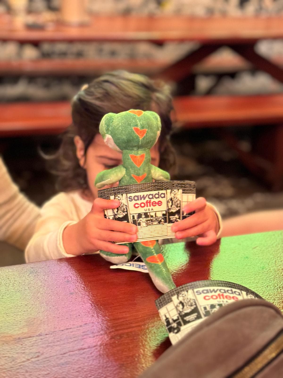 my toddler with her gecko stuffed animal inside of a coffeeshop