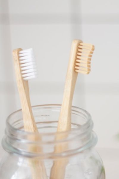 2 wooden toothbrushes in a glass jar