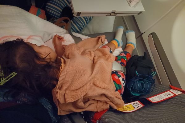 my little sleeping on my lap on the plane - an important item on the tips for flying with a toddler list