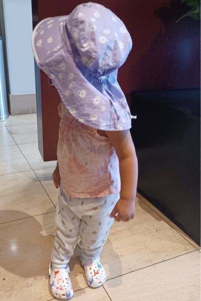 my toddler looking back to the wall in her purple sunhat