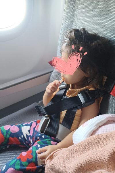 my toddler enjoying a lollipop, buckled in on the plane, prior to take off