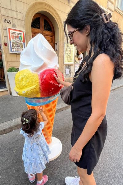 my toddler enjoying an ice cream cone fixture outside of a shop in Rome - after we used all of our tips for flying with a toddler!