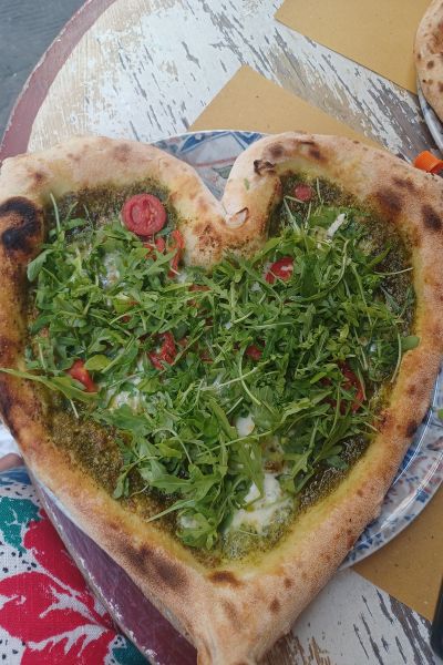 heart shaped pizza with arugula and tomatoes on top